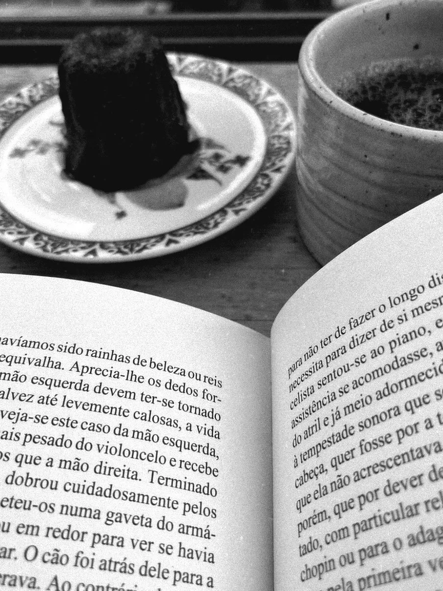 An open book next to a plate and a cup of tea
