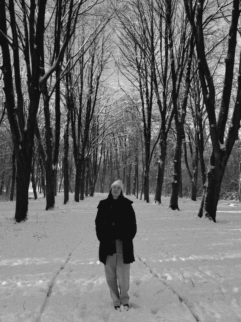 A person walking down a snowy, tree-lined path